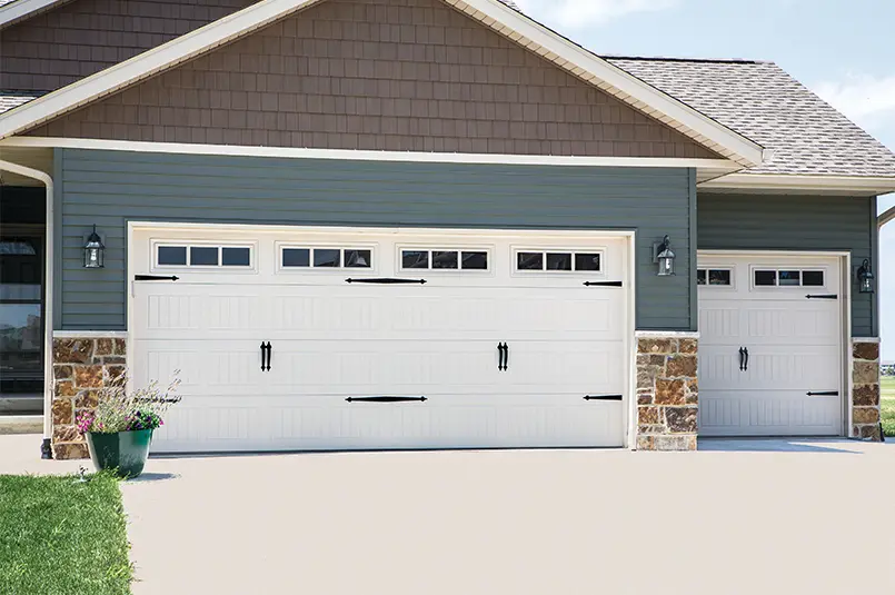 Traditional steel garage doors in white, featuring embossed wood-grain texture and decorative hardware, enhancing curb appeal and durability for residential properties.