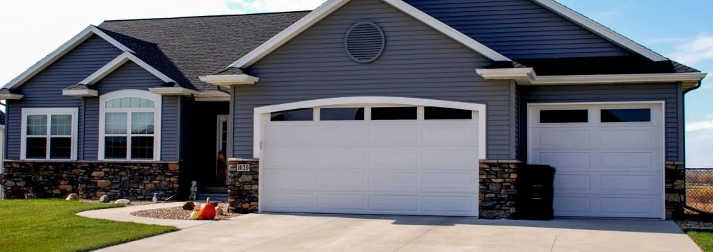 Traditional steel garage doors on a modern home with stone accents, showcasing curb appeal and security features relevant to Overhead Door™ of Sacramento services.