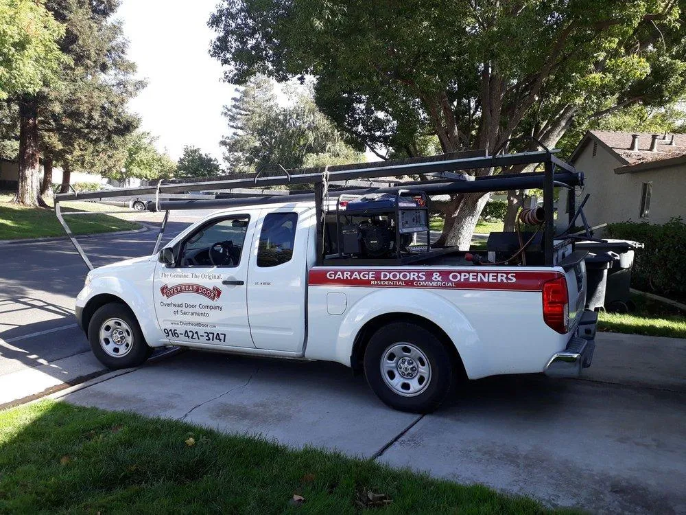 Homeowner performing maintenance on a garage door, lubricating hinges and checking for wear